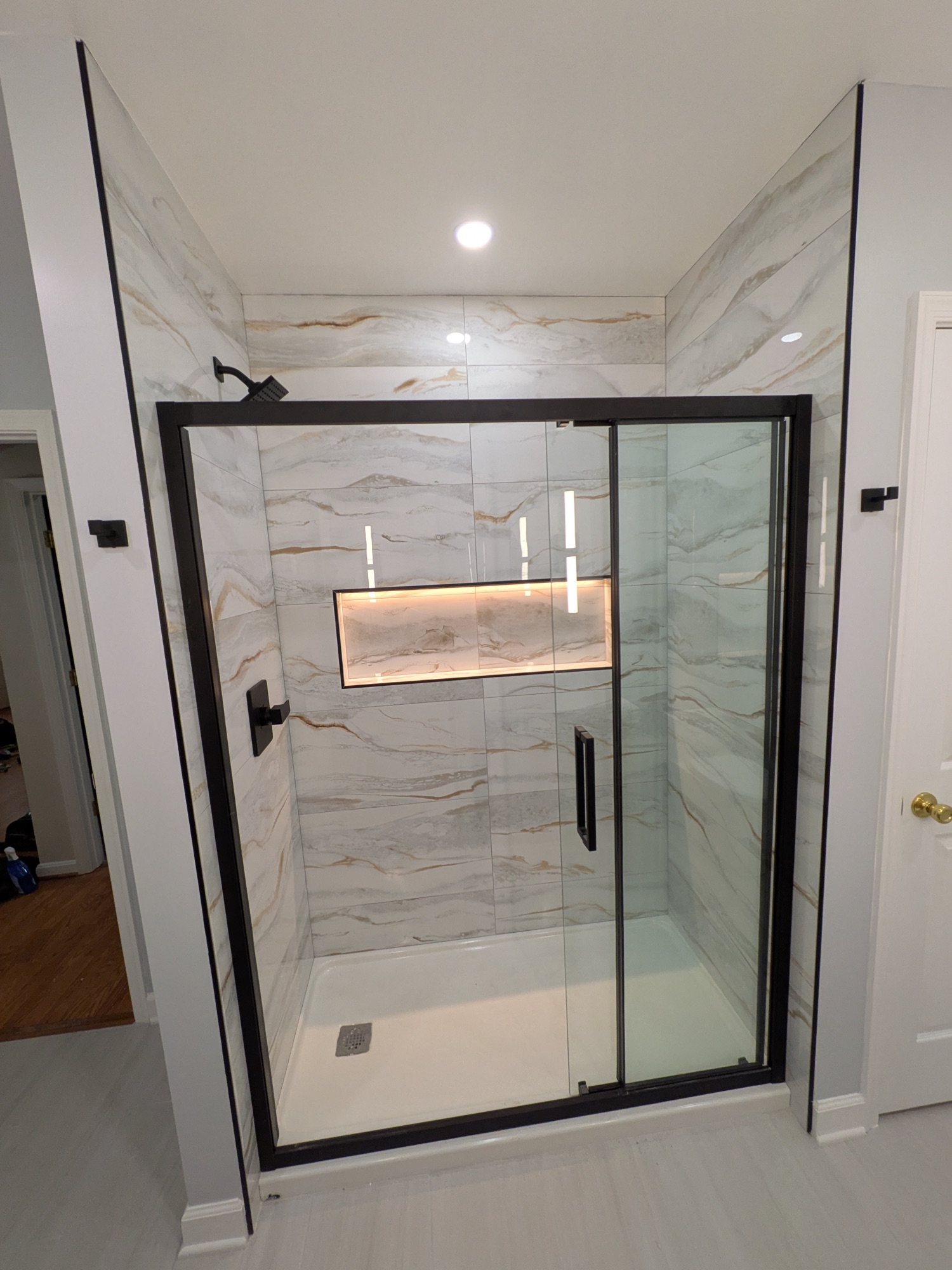 Finished shower with book-matched porcelain and a backlit niche